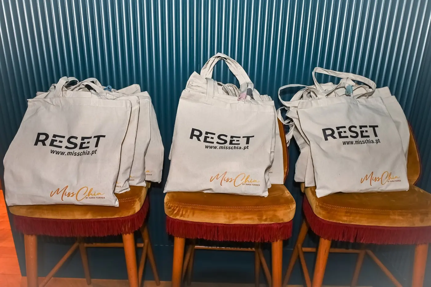 Sacos de pano com a palavra RESET, pousados em três cadeiras.