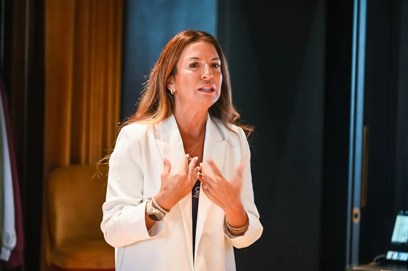 Sara Torres de casaco branco, a falar, com as mãos no peito.