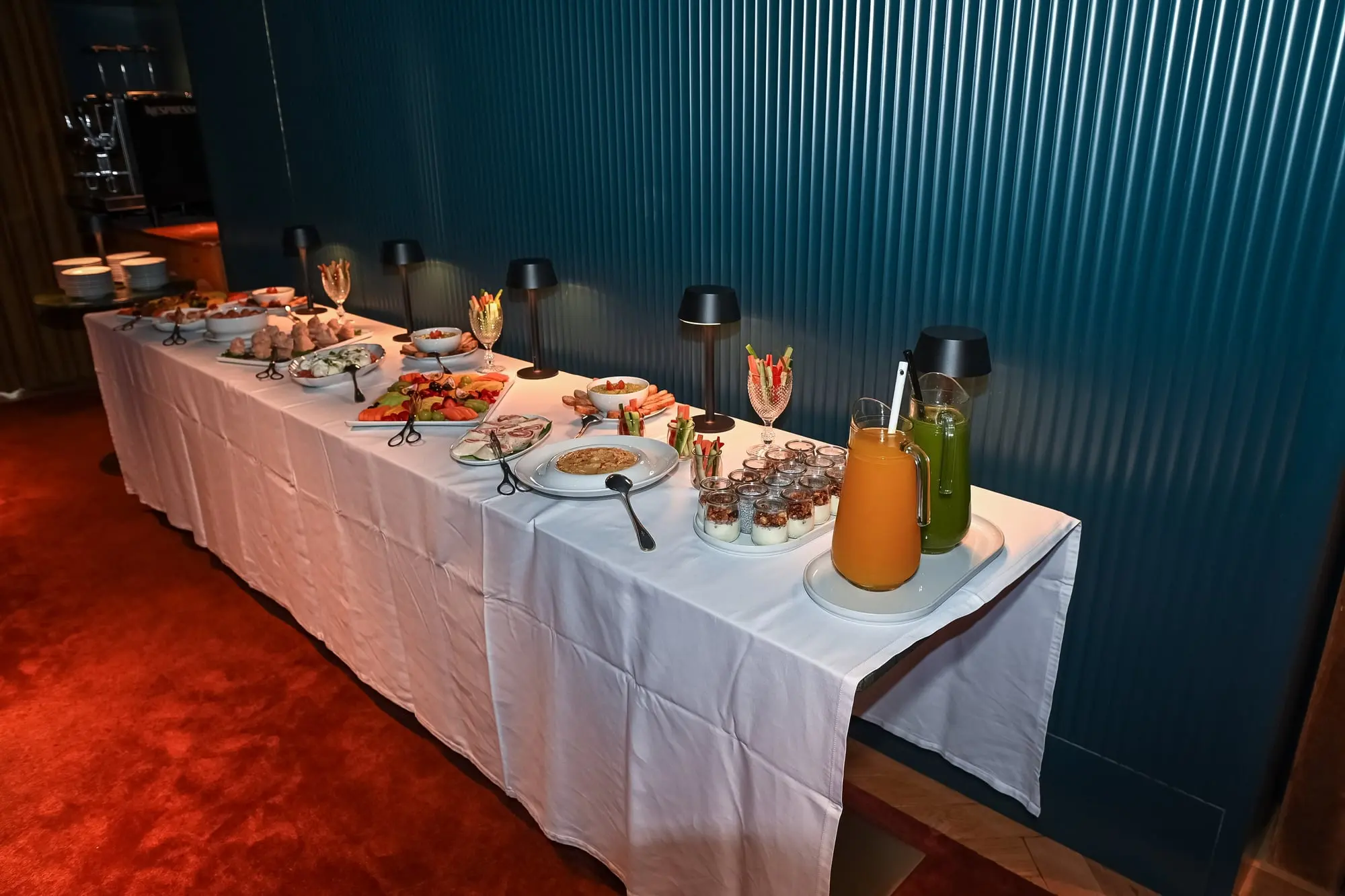 A mesa do brunch, comprida, com travessas e jarros de sumo.