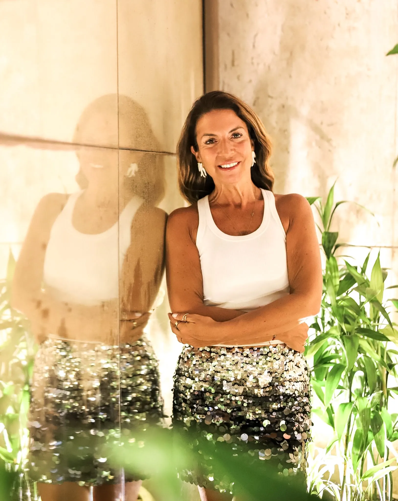 Sara Torres, a sorrir, de braços cruzados, junto a plantas.